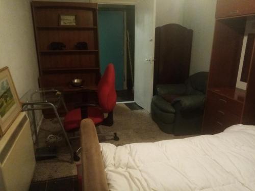 een slaapkamer met een bed, een stoel en een bureau bij Flat 30 brookeshouse in Walsall