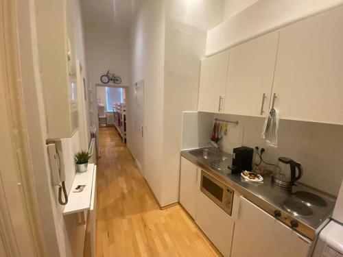 een keuken met witte kasten en een houten vloer bij Cozy appartm with + airport/city center connection in Wenen