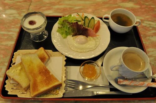 a tray with two plates of food and two cups of coffee at Hotel Los Inn Kochi in Kochi