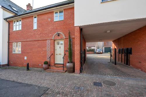 a brick building with a white door and a cactus at 2 Bedroom stylish property set behind the angel hotel with parking and a courtyard garden in Bury Saint Edmunds