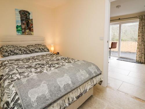 Schlafzimmer mit einem Bett und einer Tür zu einer Terrasse in der Unterkunft Yemble Rose in Cardigan