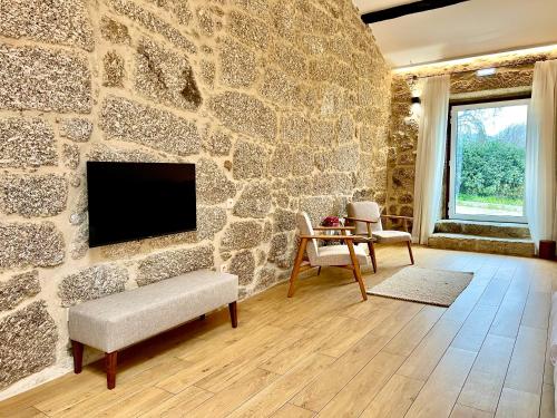 a living room with a stone wall with a tv at Quinta da Porta - Solar de Vale de Prazeres in Vale de Prazeres