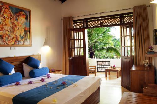 a bedroom with a large bed with a large window at Sky and Sand Guesthouse in Beruwala