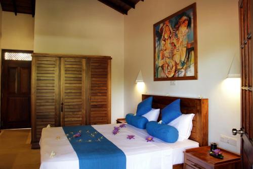 a bedroom with a large bed with blue pillows at Sky and Sand Guesthouse in Beruwala