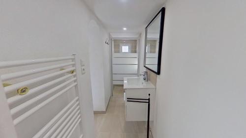 een witte badkamer met een wastafel en een spiegel bij Gîte « l’Escapade Cabassoise » in Cabasse
