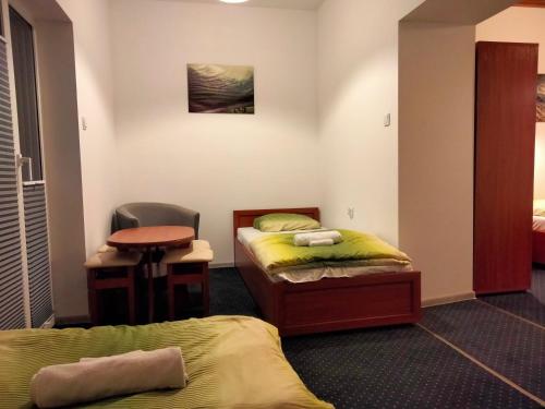 a room with two beds and a desk and a table at U Gumisia in Korbielów
