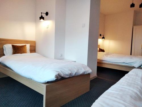 two beds in a room with white sheets at U Gumisia in Korbielów