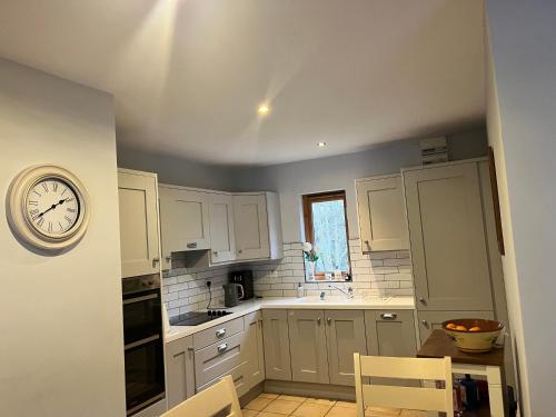 a kitchen with white cabinets and a clock on the wall at Beautiful Riverside Retreat in Blackwater, Wexford in Blackwater