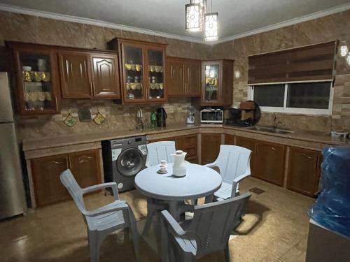 eine Küche mit einem Tisch und weißen Stühlen in der Unterkunft Cozy House in Wadi Musa