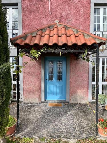 a blue door of a pink house with a red roof at Quinta Belmonte with Private Heated Pool in Funchal in Funchal