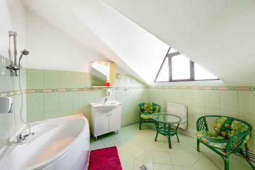 a bathroom with a tub and a table and chairs at Pensiunea Casa Zanelor in Floreşti