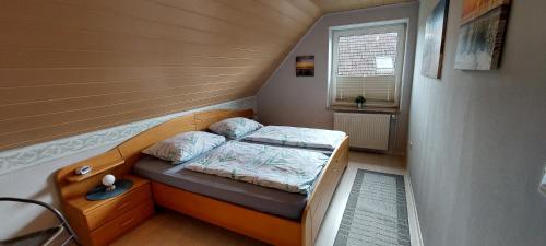 Cama pequeña en habitación pequeña con ventana en Haus im Wiesengrund, en Esens