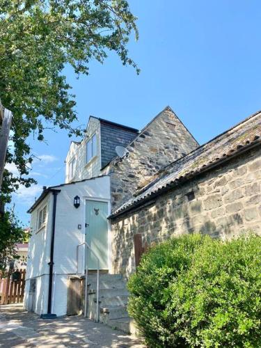 an old stone building with a white door and stairs at Coquetdale Cottage in Rothbury, Nr National Park in Rothbury