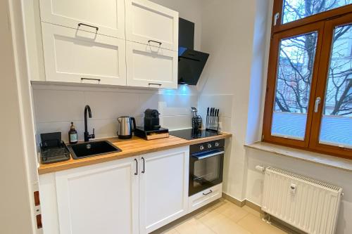 a kitchen with white cabinets and a sink and a window at Business - YR Apartment - Citynah, WLAN, Drucker in Chemnitz