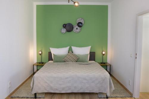 1 dormitorio con 1 cama con pared verde en Business-Apartment - Citynah, WLAN, Drucker, Netflix & Parken en Chemnitz