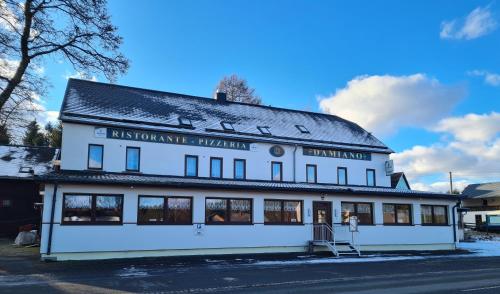 a white building with a black roof at Pizzeria Pension Damiano in Muldenhammer