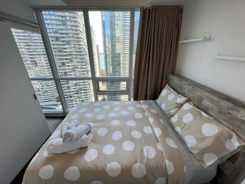 a bed in a room with a large window at Centrally Located - Spacious 2-Bdrm Condo - Next to Scotiabank Arena in Toronto