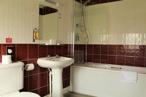 a bathroom with a sink and a tub and a toilet at The Oakwheel in Scarborough