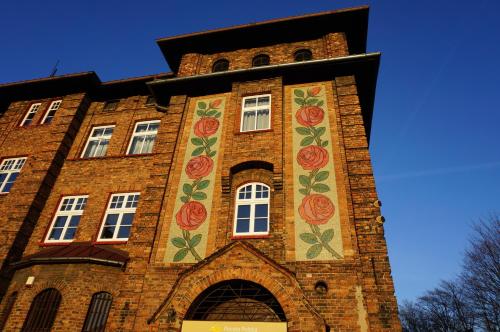 a tall brick building with flowers painted on it at Kolorowy apartament A9 Katowice Nikiszowiec in Katowice