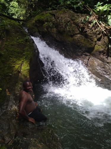 a man sitting on a rock next to a waterfall at Cabaña Villa Sofi in Nuquí