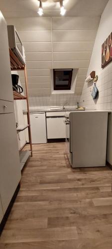 cocina con electrodomésticos blancos y suelo de madera en Haus im Wiesengrund, en Esens