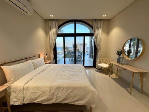 sypialnia z łóżkiem i dużym oknem w obiekcie The Beach House w Maskacie