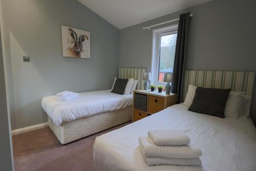 a bedroom with two beds and a window at Beautiful Oak Cabin in Devon Finlake Resort Spa in Chudleigh