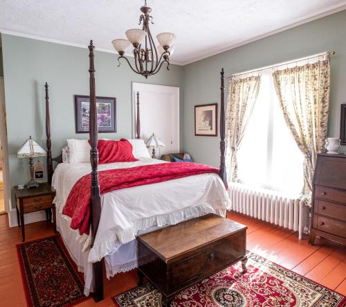a bedroom with a bed with a red blanket at The Lark & Loon Inn in Annapolis Royal
