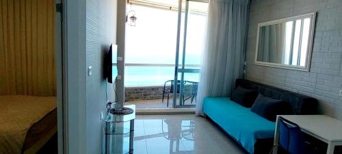 a room with a couch and a view of the ocean at Apart Hotel TLV/Bat Yam Beach Front 1207 in Bat Yam