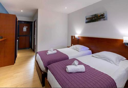 two beds in a hotel room with towels on them at SAS CLP - La Marina in Kourou