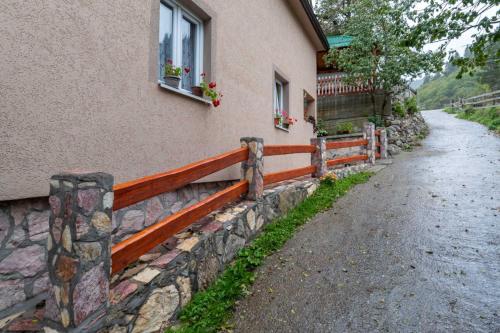 a house with a stone fence next to a street at HOUSEHOLD MIKO MERDOVIC - 15e per person in Berane