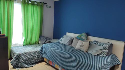 1 dormitorio con 1 cama y una ventana con cortinas verdes en CASA CON PILETA EN VILLA ATILIA, LUJAN DE CUYO en Luján de Cuyo