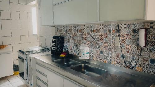 cocina con fregadero y pared de azulejos en Apartamento a 200 metros da feirinha da beira mar en Fortaleza