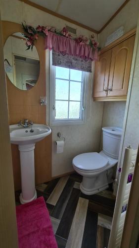 a bathroom with a toilet and a sink and a window at Caravan 6 berth in Ingoldmells