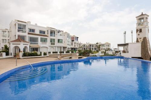 uma grande piscina azul em frente a alguns edifícios em appartement de luxe front mer à DAR BOUAAZA em Dar Bouazza