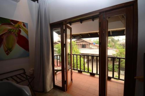 a room with a door open to a balcony at Moonlight Champa Riverview in Luang Prabang