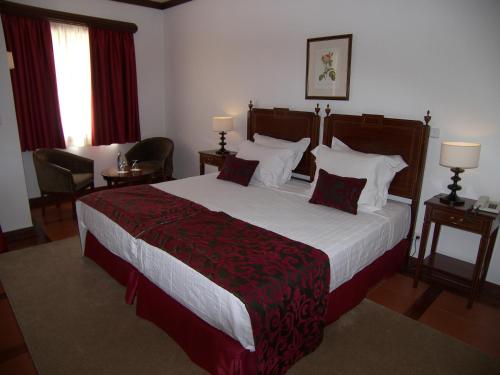 a bedroom with a large bed with red and white pillows at Hotel Rural Quinta de Santo Antonio in Elvas