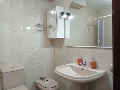 ein Badezimmer mit Waschbecken, Toilette und Spiegel in der Unterkunft Piso A Capela con vistas al mar in Fisterra