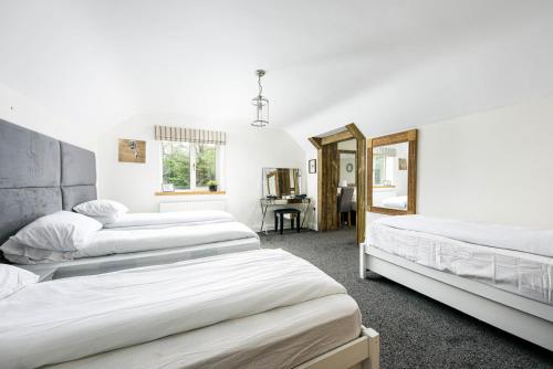 a bedroom with three beds and a mirror at Cheerful 7-bedroom house with hot tub sleeps 24 in Iron Acton