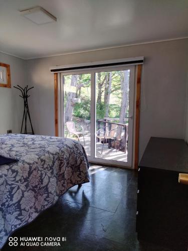 a bedroom with a bed and a sliding glass door at Cabaña con Tinaja Privada Ruta 657 in Coihaique
