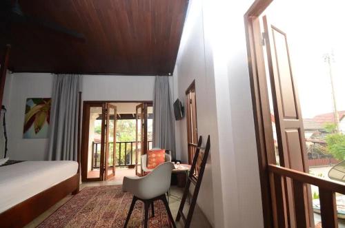 a bedroom with a bed and a table and a chair at Moonlight Champa Riverview in Luang Prabang