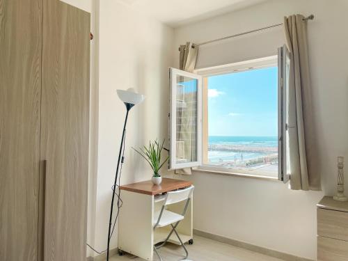 a room with a desk and a window with a view of the beach at Demetra Seafront Apartment - Parking & Pool in Castel Volturno