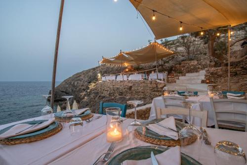 a table with white tables and chairs in front of the ocean at Relais Isole del Sud in Lampedusa