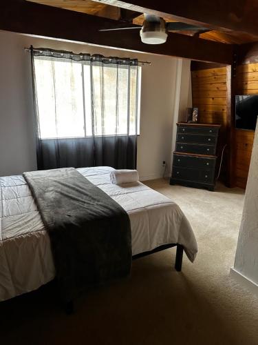 a bedroom with a bed and a dresser and a window at Cozy Crescent Tree Cabin Near Bear Mountain in Big Bear Lake