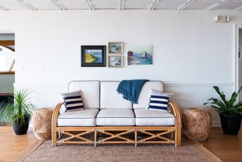 a living room with a rattan couch with pillows at Wylder Hotel - Tilghman Island in Saint Michaels