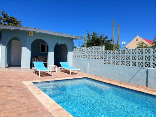 a swimming pool with two chairs and a house at Apartment Villa Valentina in Noord