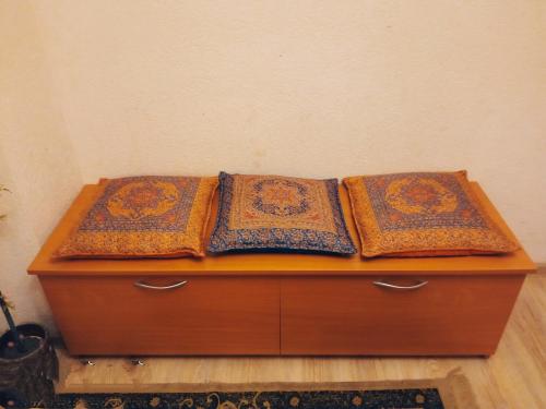 drie kussens bovenop een houten dressoir bij Apartamentai in Tauragė
