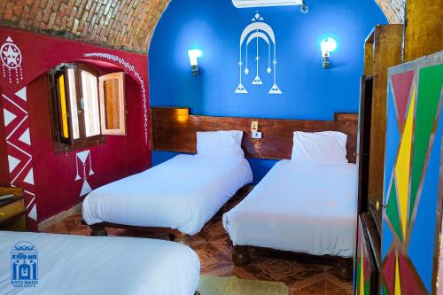 2 camas en una habitación con paredes azules y rojas en Kato Waidi Nubian Resort en Asuán
