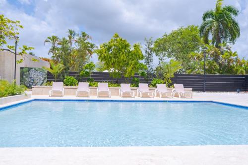 a swimming pool with lounge chairs and a swimming pool at Xeliter Green One Playa Dorada in San Felipe de Puerto Plata