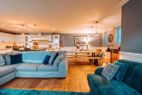 a living room with blue couches and a kitchen at The Vestry - Sleeps 12 - With Hot Tub in Haworth